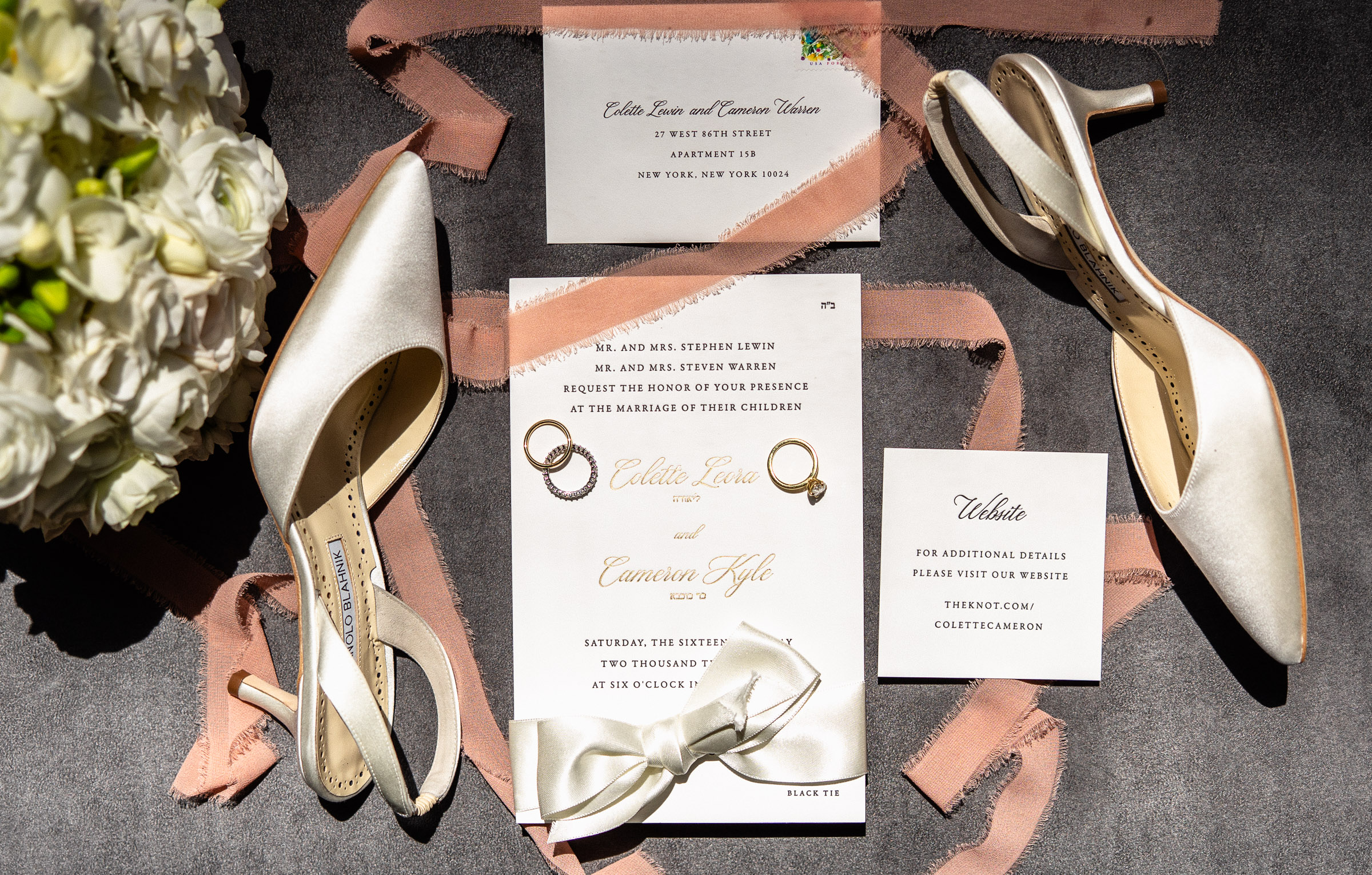 Wedding invitation suite with white heels, rings, ribbon, and flowers