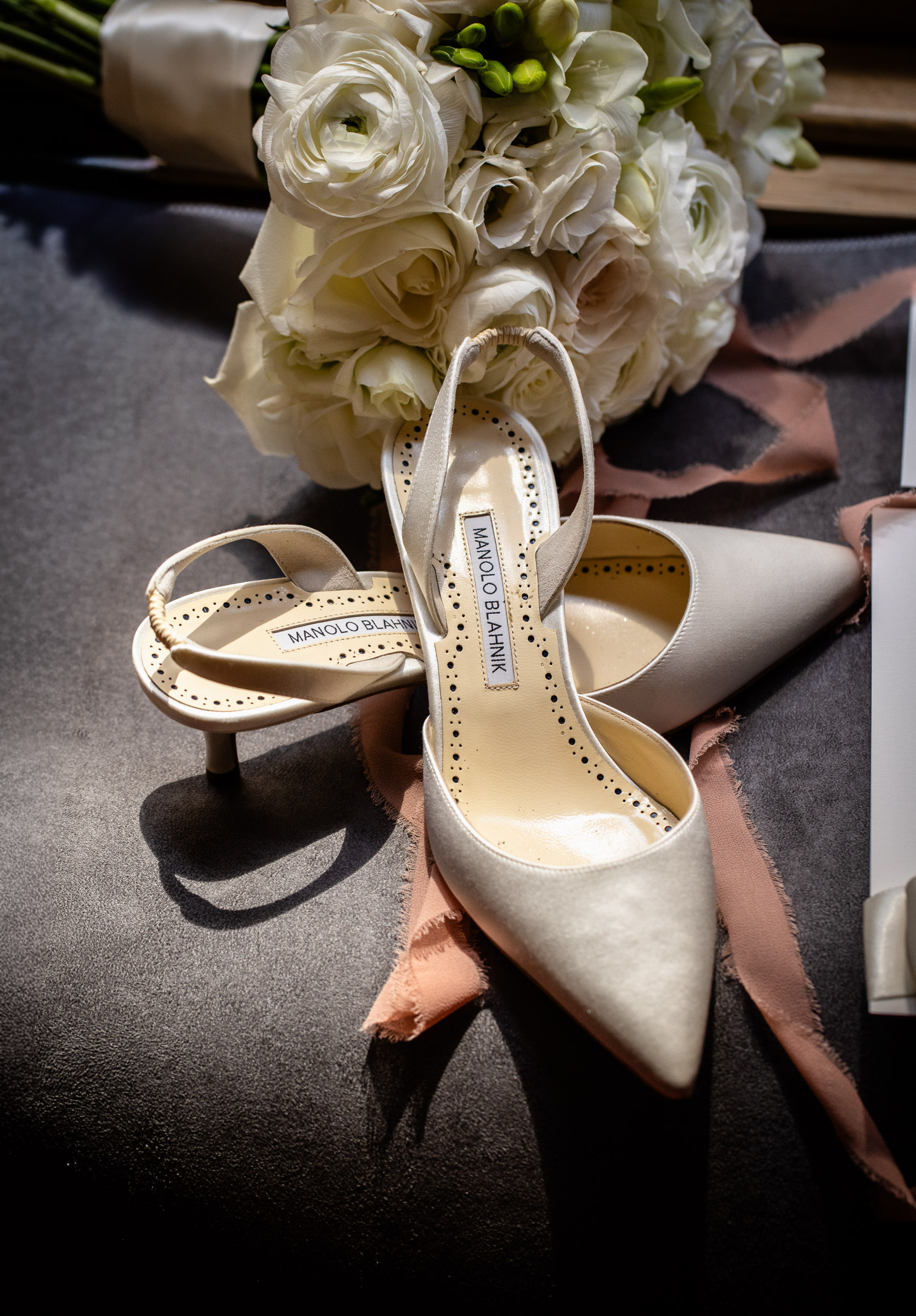 Wedding rings arranged beside the bride's white shoes