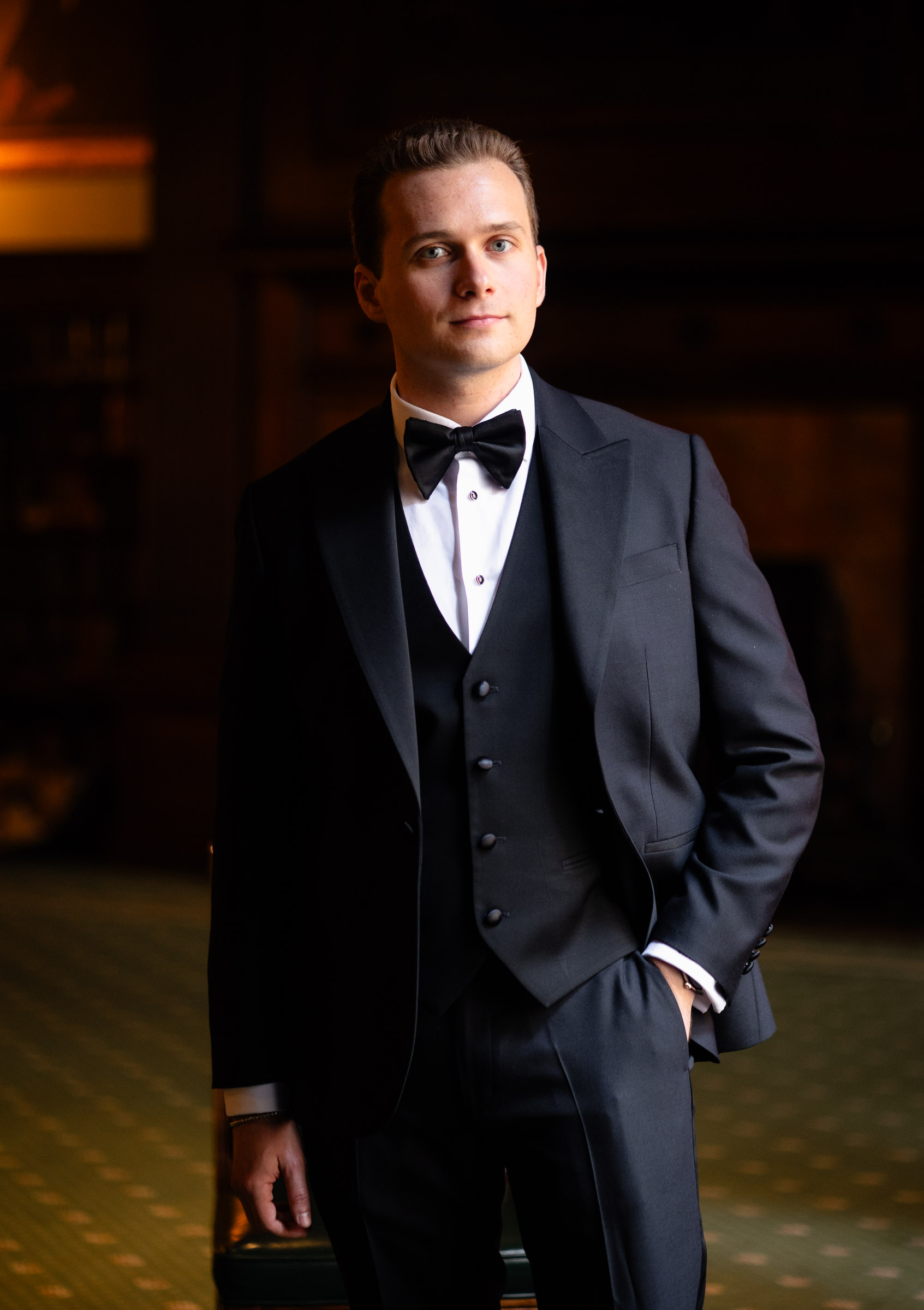 Cameron standing for a groom portrait in the Metropolitan Club library