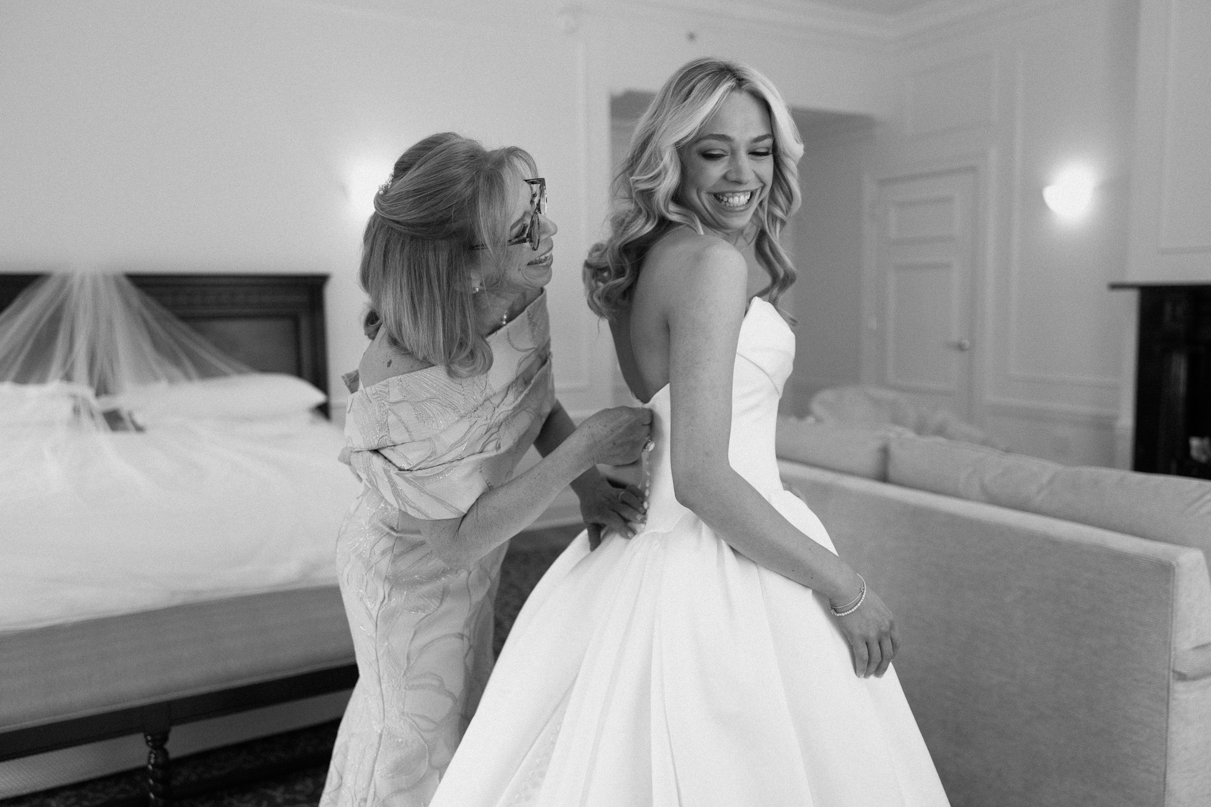 A family member helping Colette fasten her wedding dress