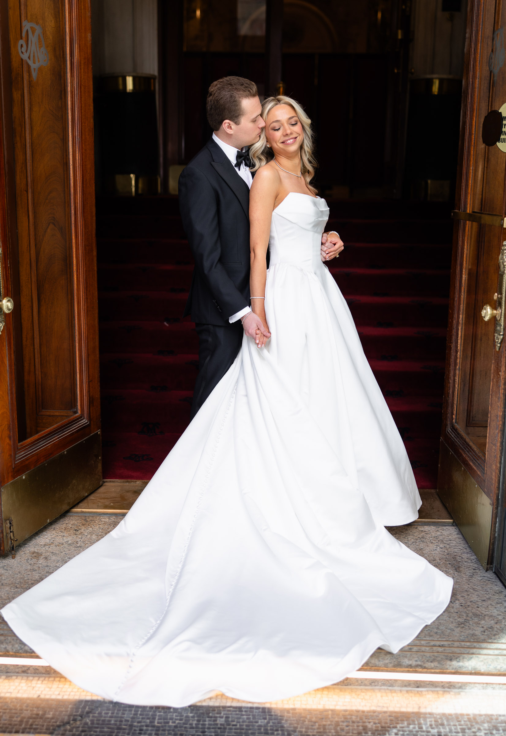 Colette and Cameron embracing in a dark wood doorway