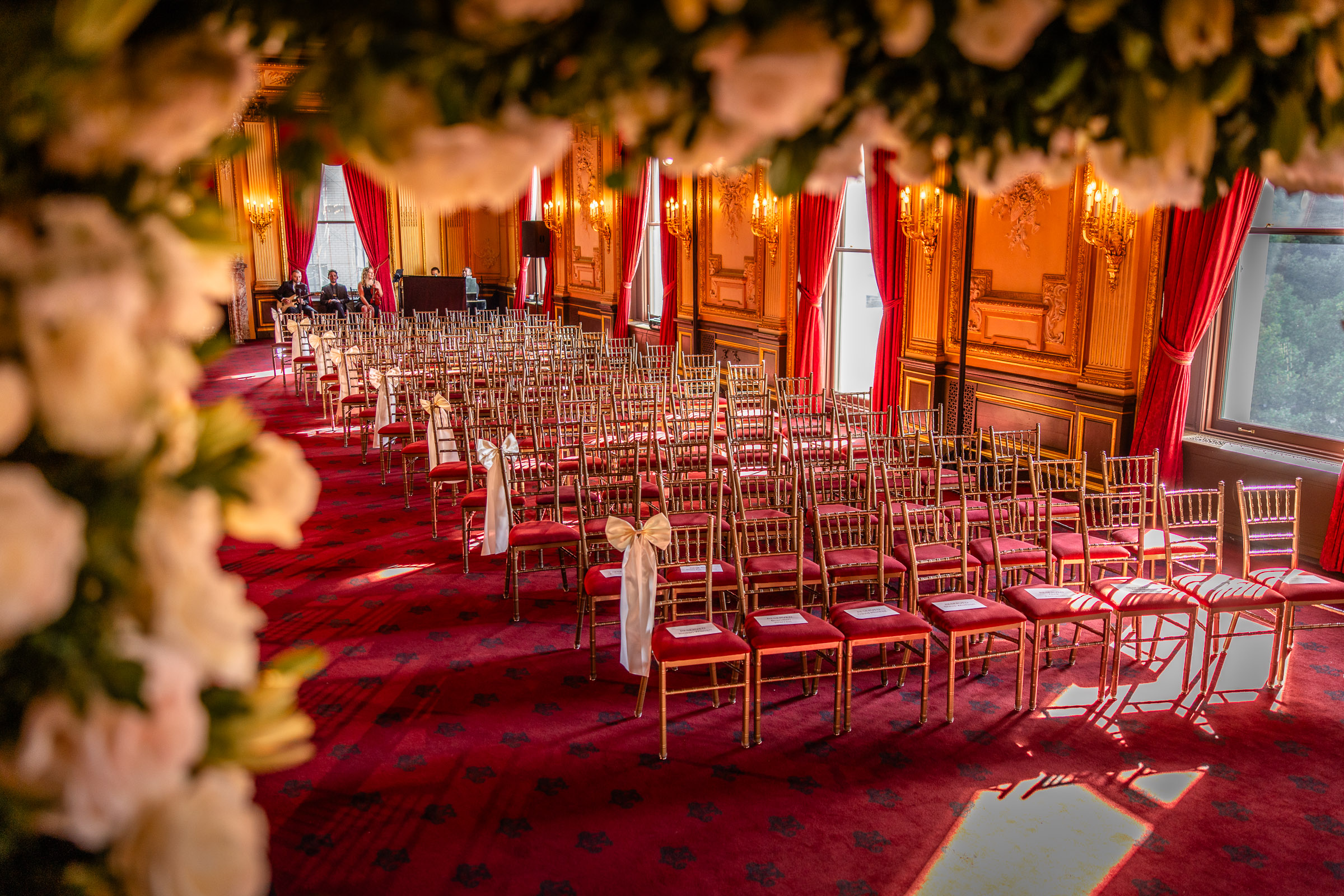 Ceremony aisle framed by white flowers and red velvet curtains