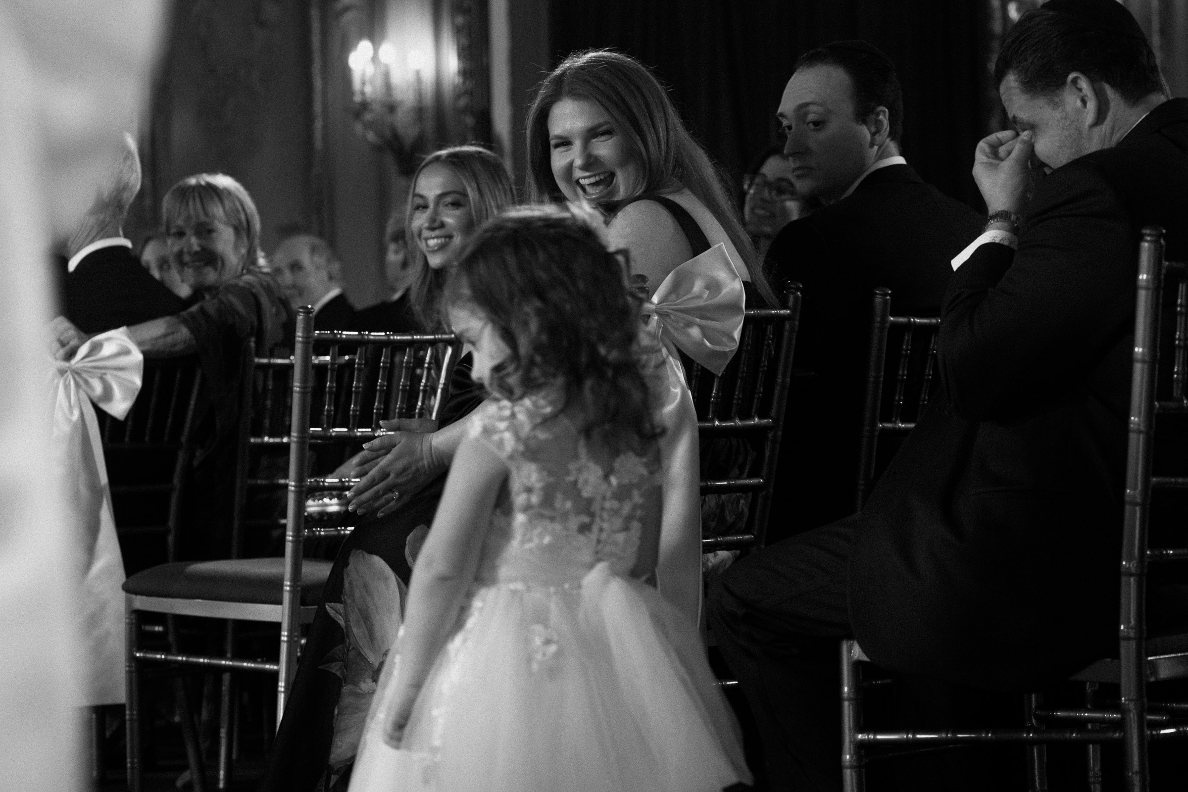 Young flower girl smiling at guests during the processional