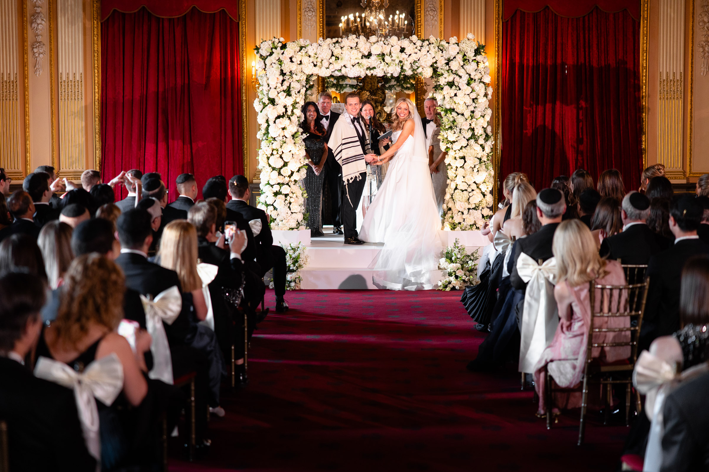 Wide view of Colette and Cameron beneath the floral chuppah