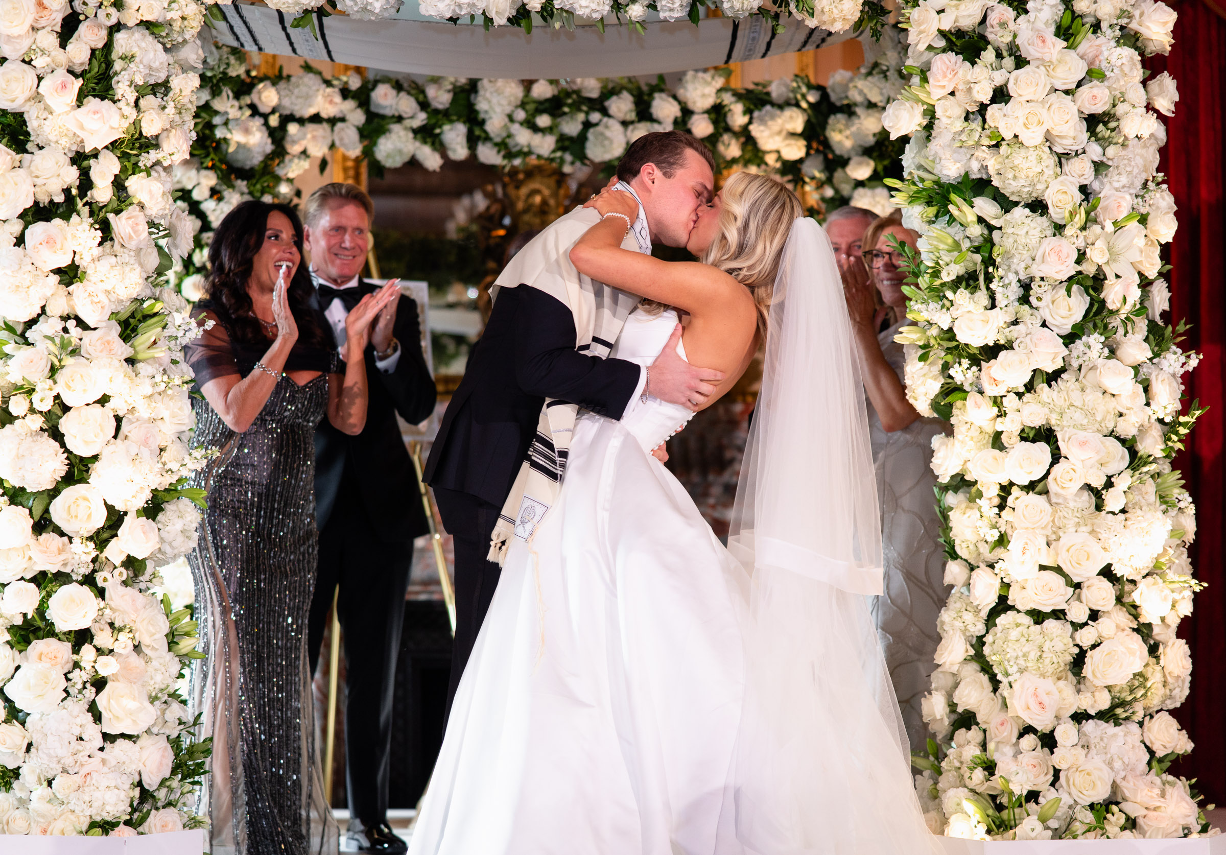 Colette and Cameron kissing beneath the white floral chuppah