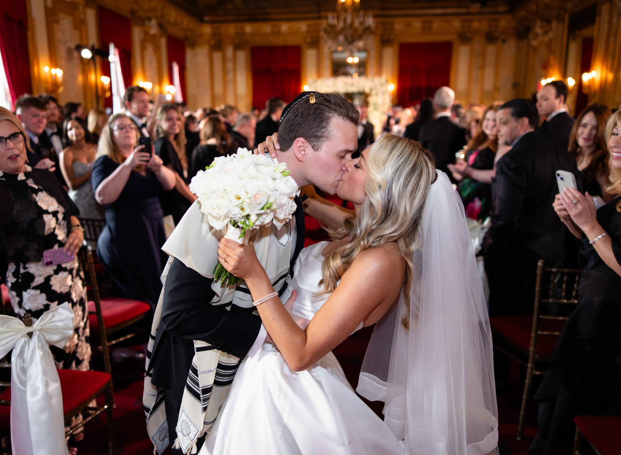 Newlyweds kissing in the aisle as guests applaud