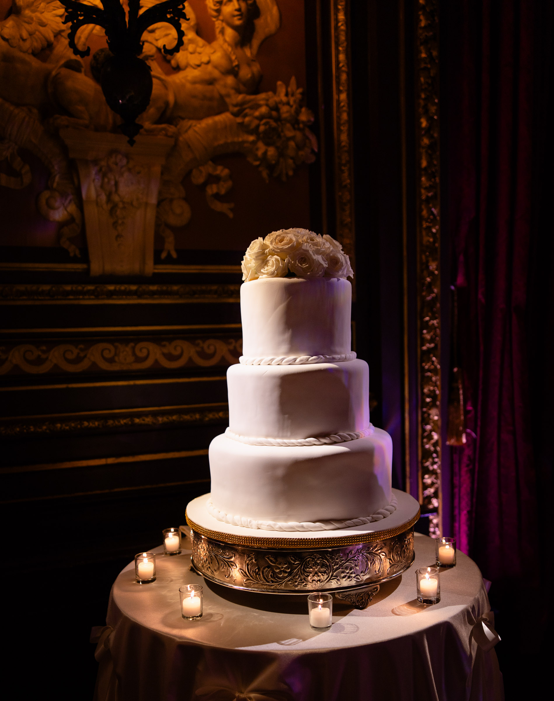 White tiered wedding cake displayed beneath a spotlight