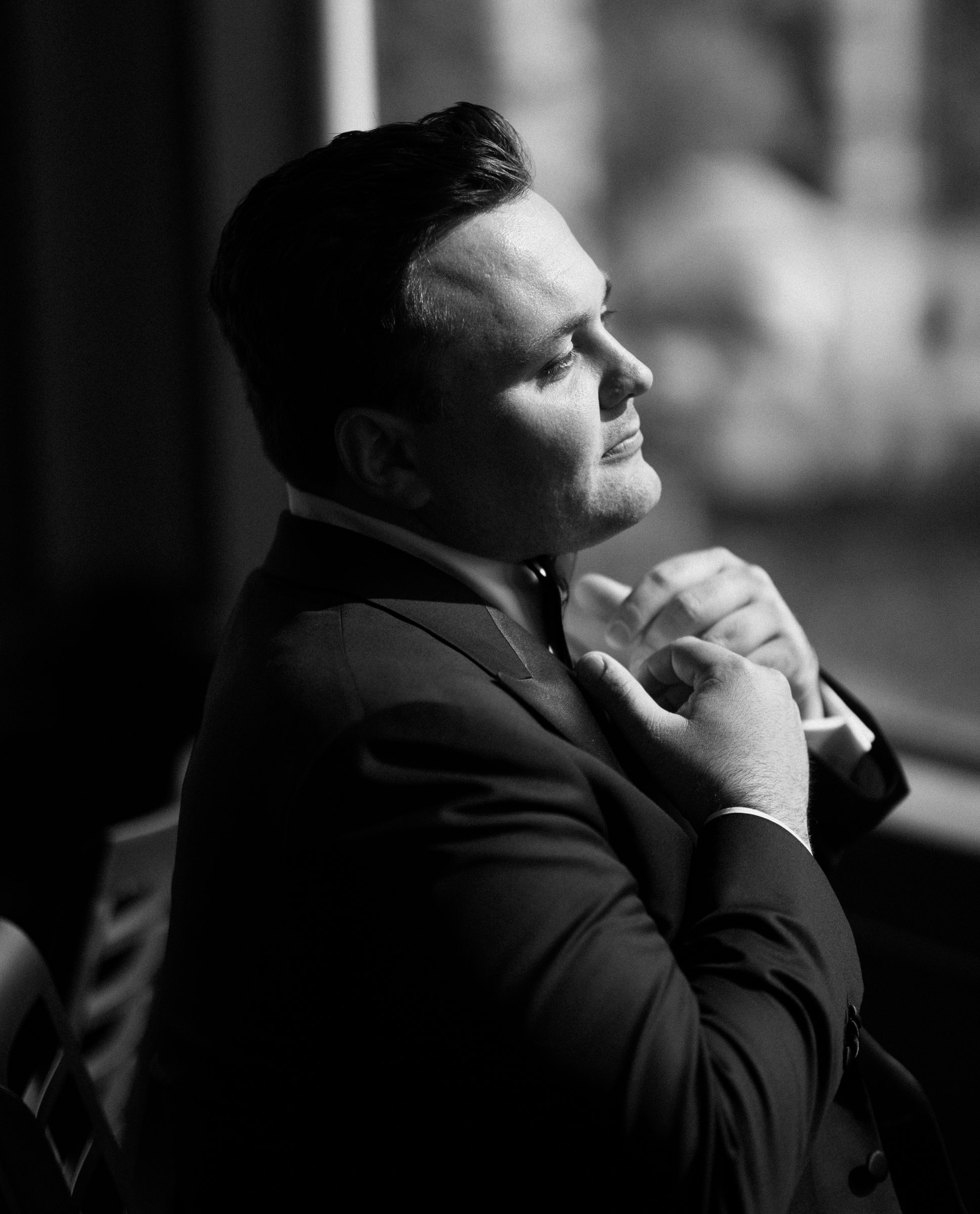 Black-and-white portrait of Austin adjusting his bow tie