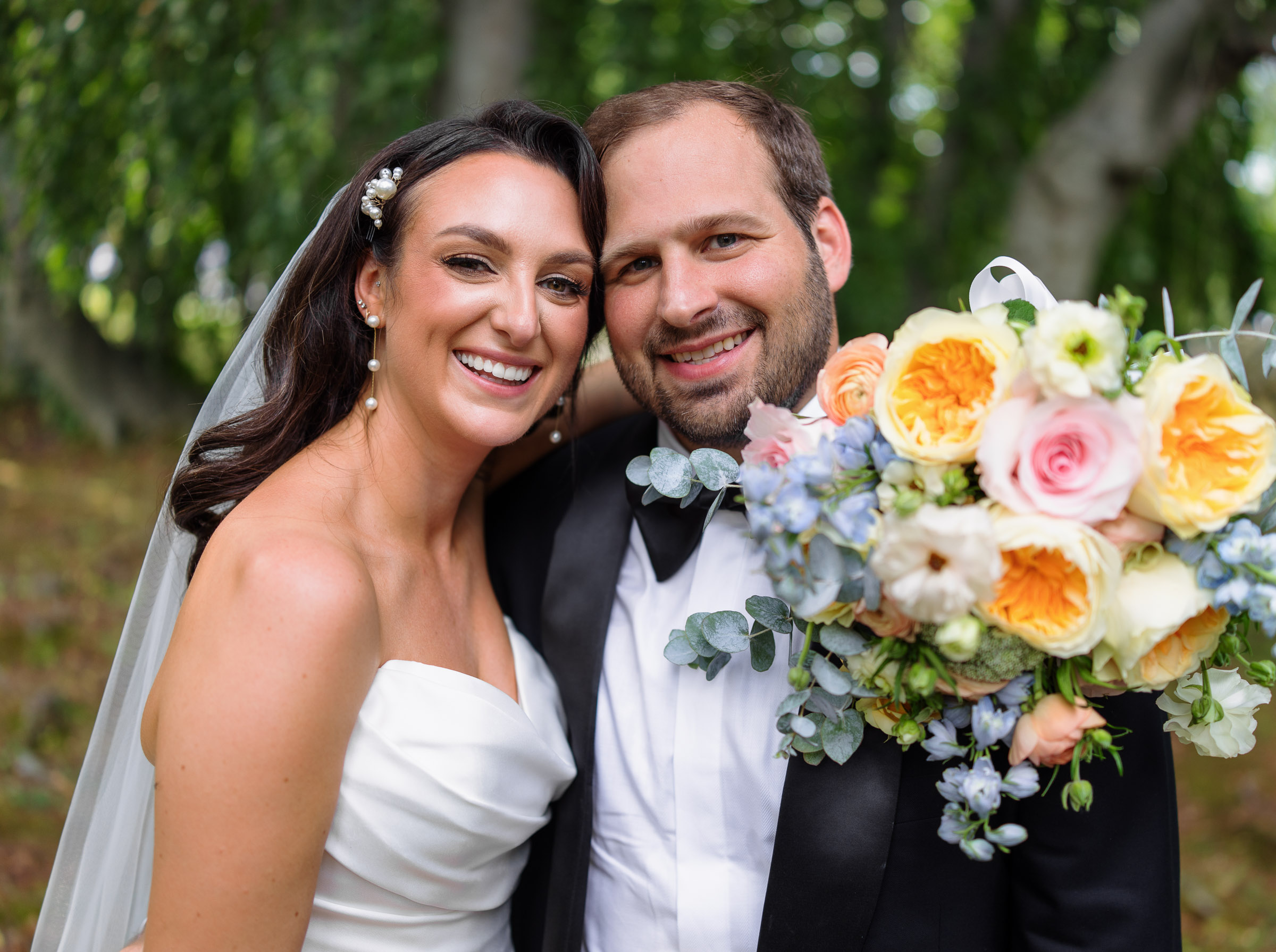 Alexandra and Ryan smiling beside their colorful bouquet