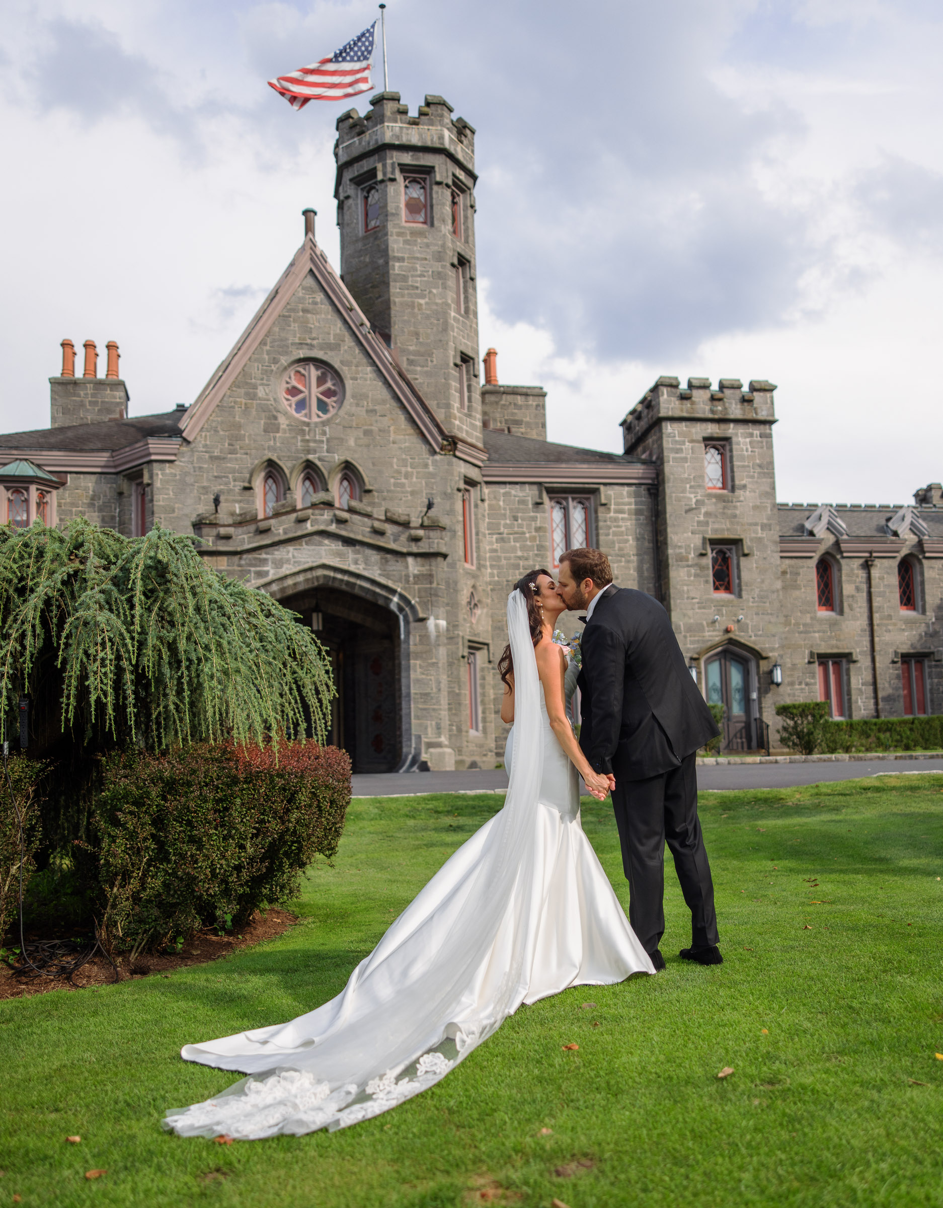 Full-length portrait of Alexandra and Ryan kissing in front of Whitby Castle