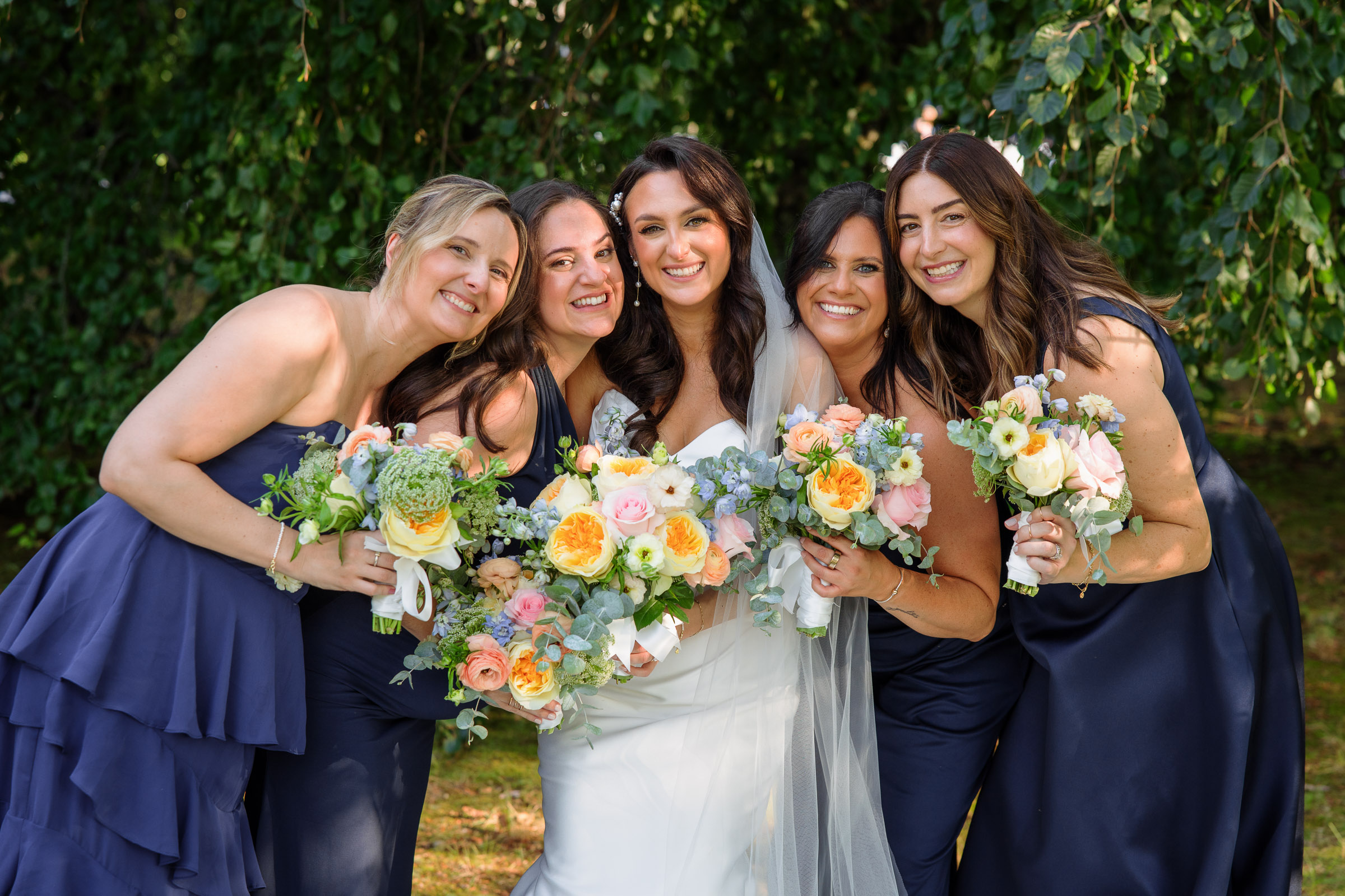 Alexandra laughing with her bridesmaids and colorful bouquets