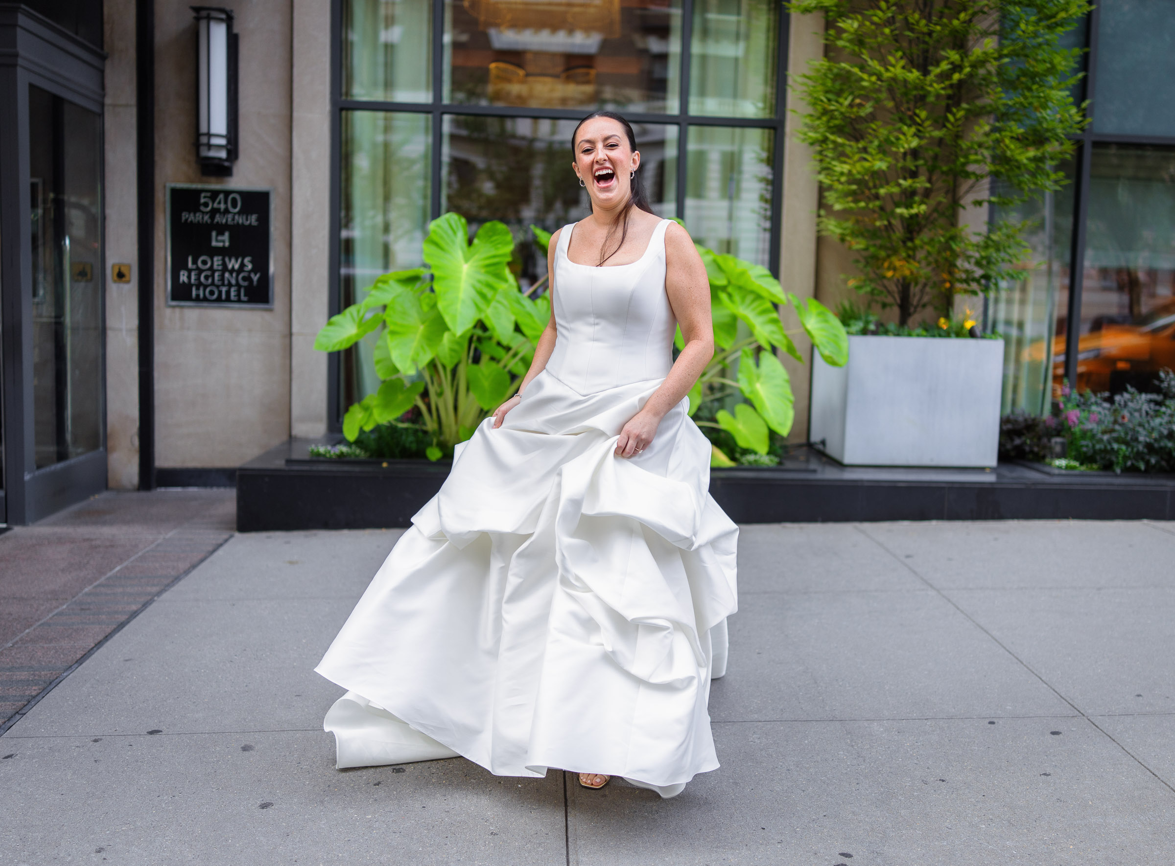 Bride lifting her layered wedding dress as she steps onto a Manhattan sidewalk