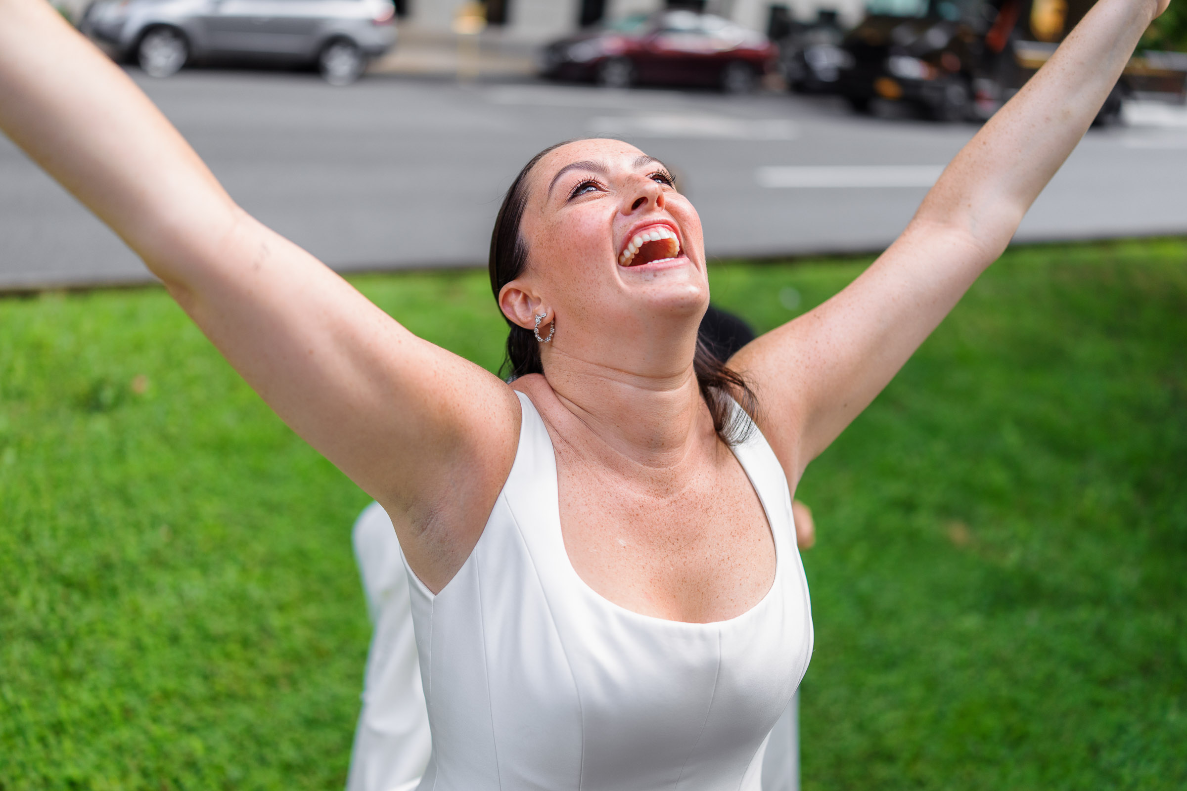 Bride laughing with her arms raised during wedding-day portraits in New York City