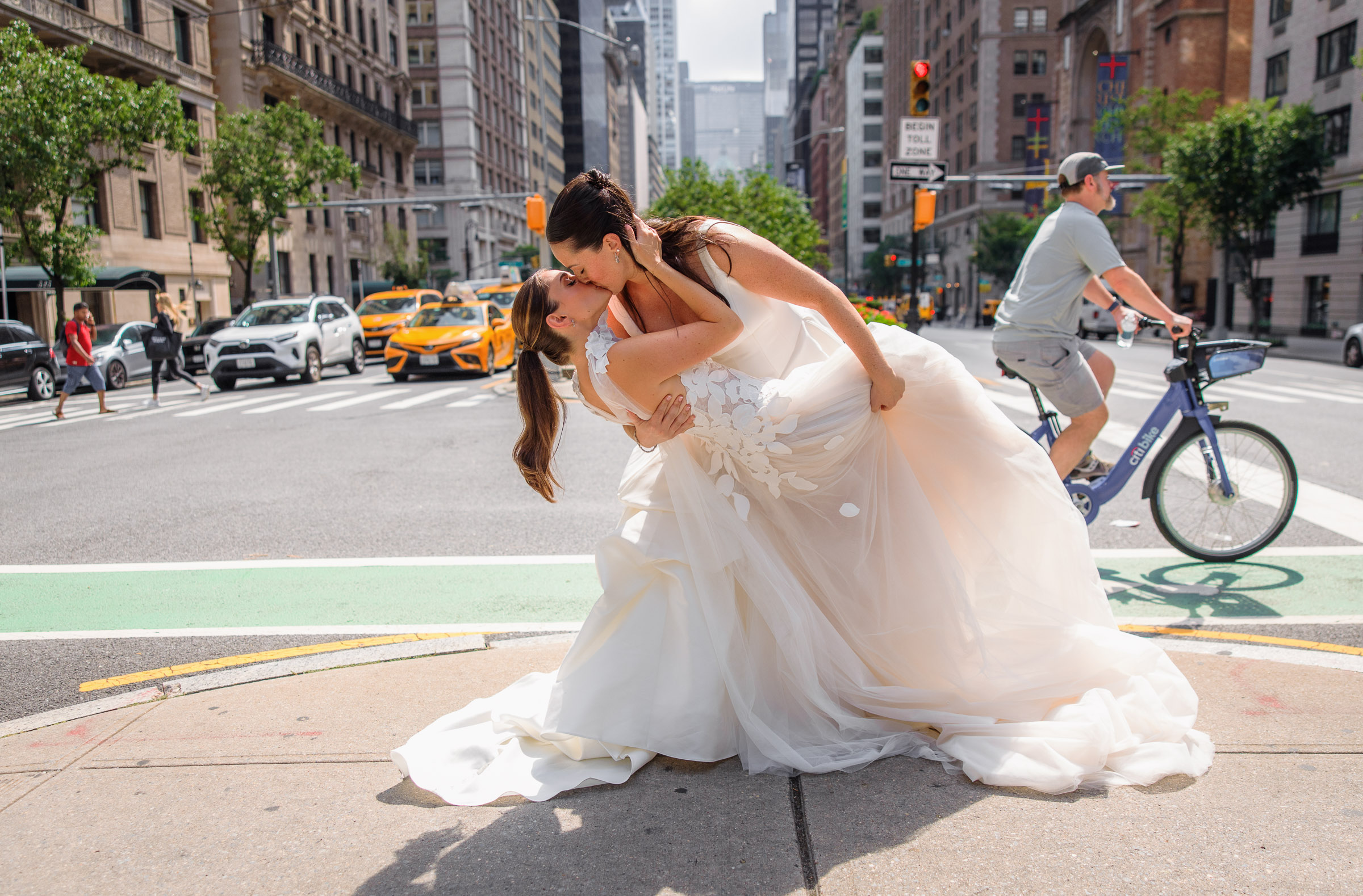 The brides sharing a playful dip and kiss in a Manhattan intersection