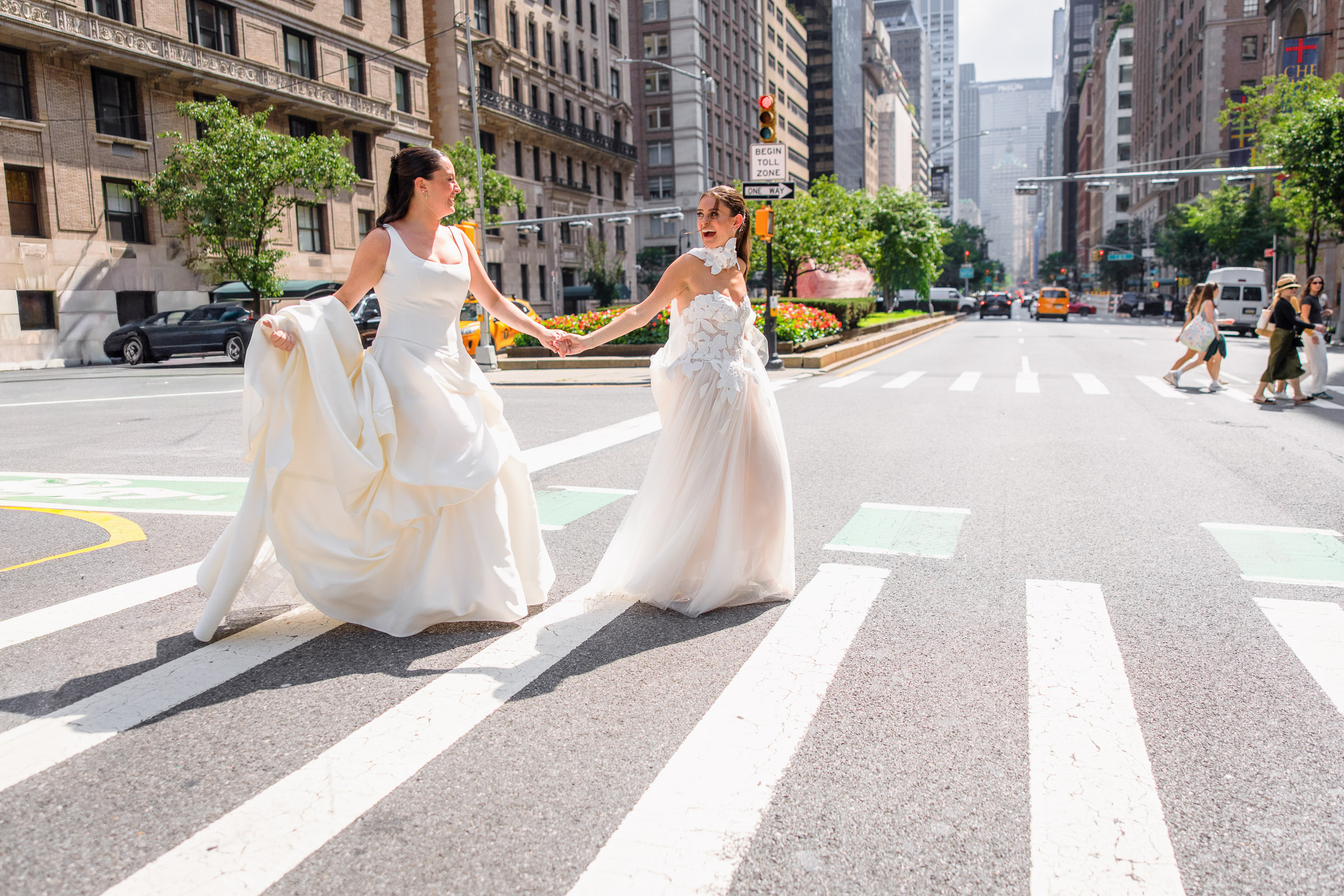 Sydney and Delilah walking across a Manhattan crosswalk in their wedding gowns
