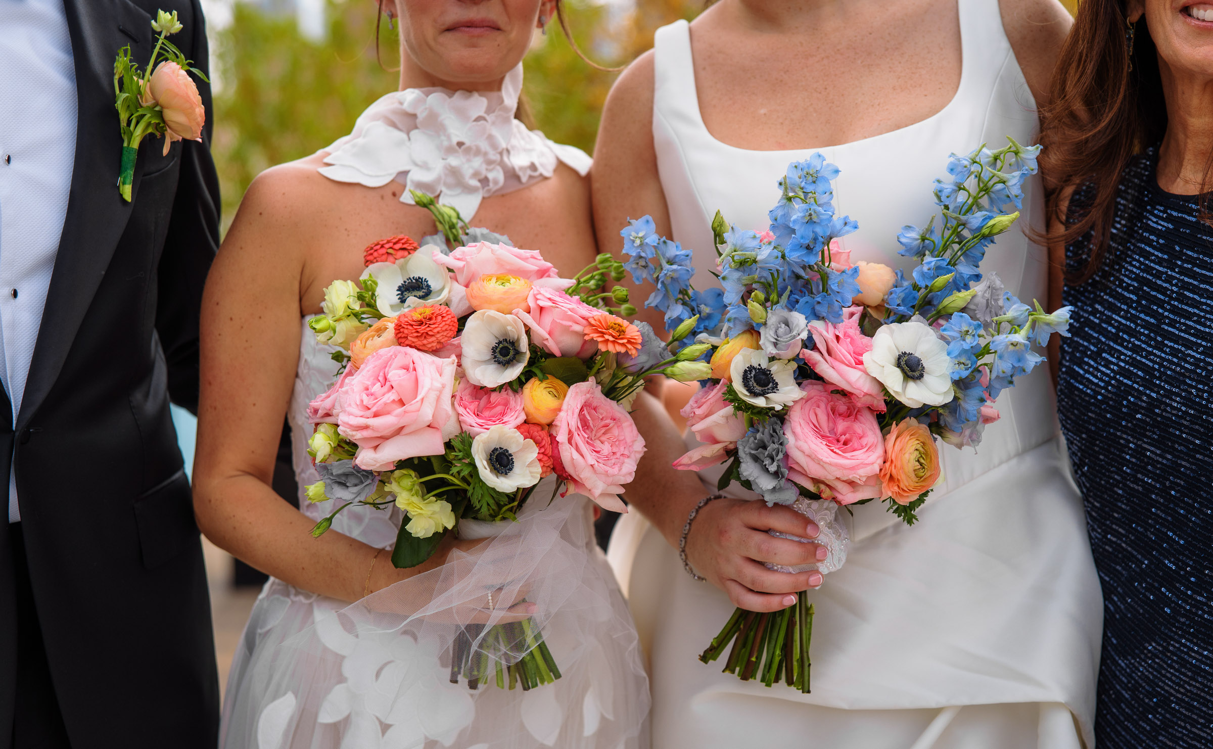 Colorful summer bouquets in pink, blue, peach, and white held by the wedding party