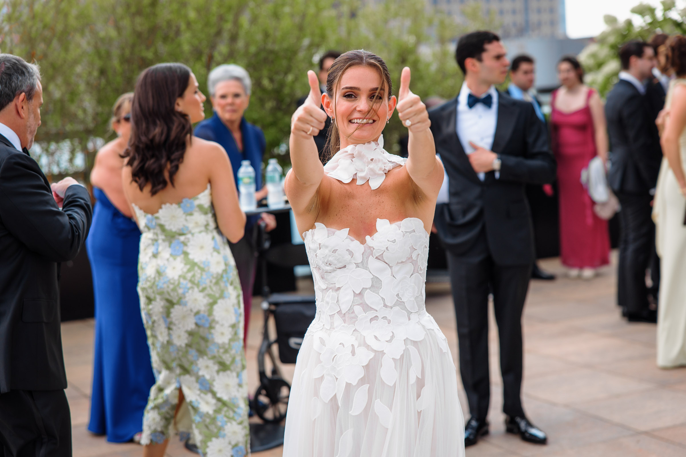 Delilah reacting with a smile as family and friends gather for rooftop photographs
