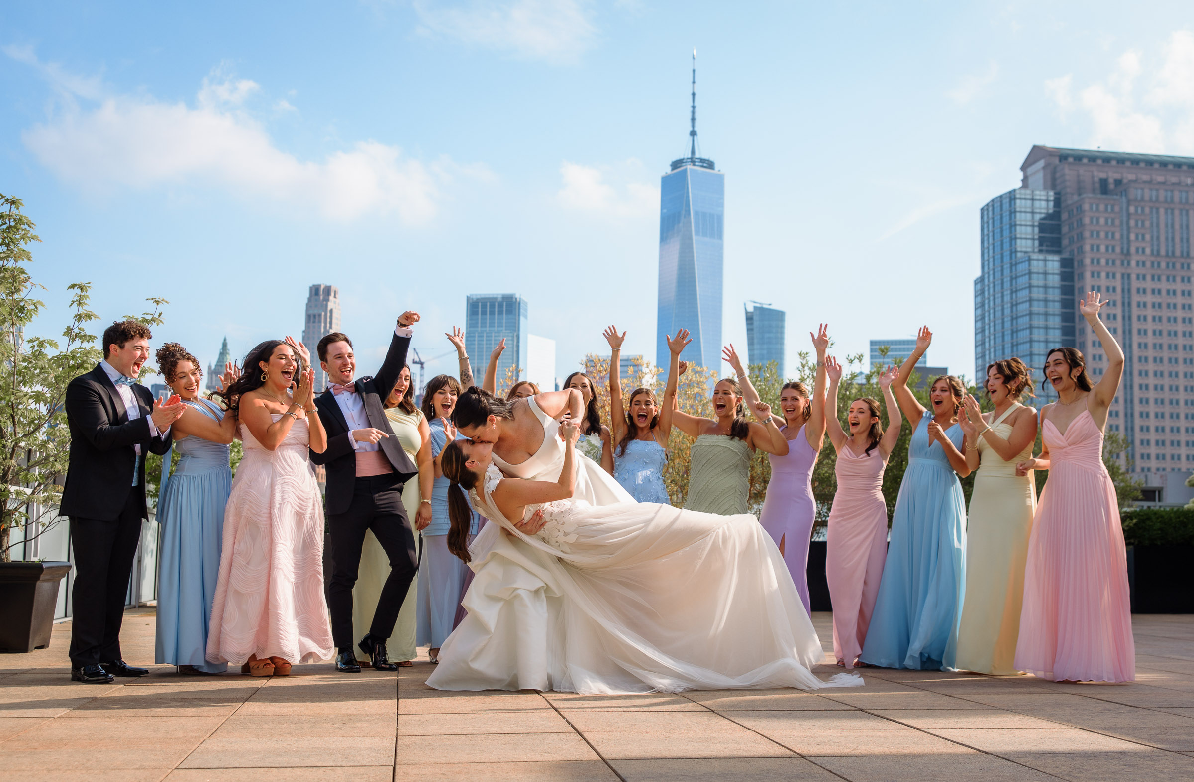 Sydney and Delilah dipping in front of their wedding party on Tribeca Rooftop with One World Trade Center behind them