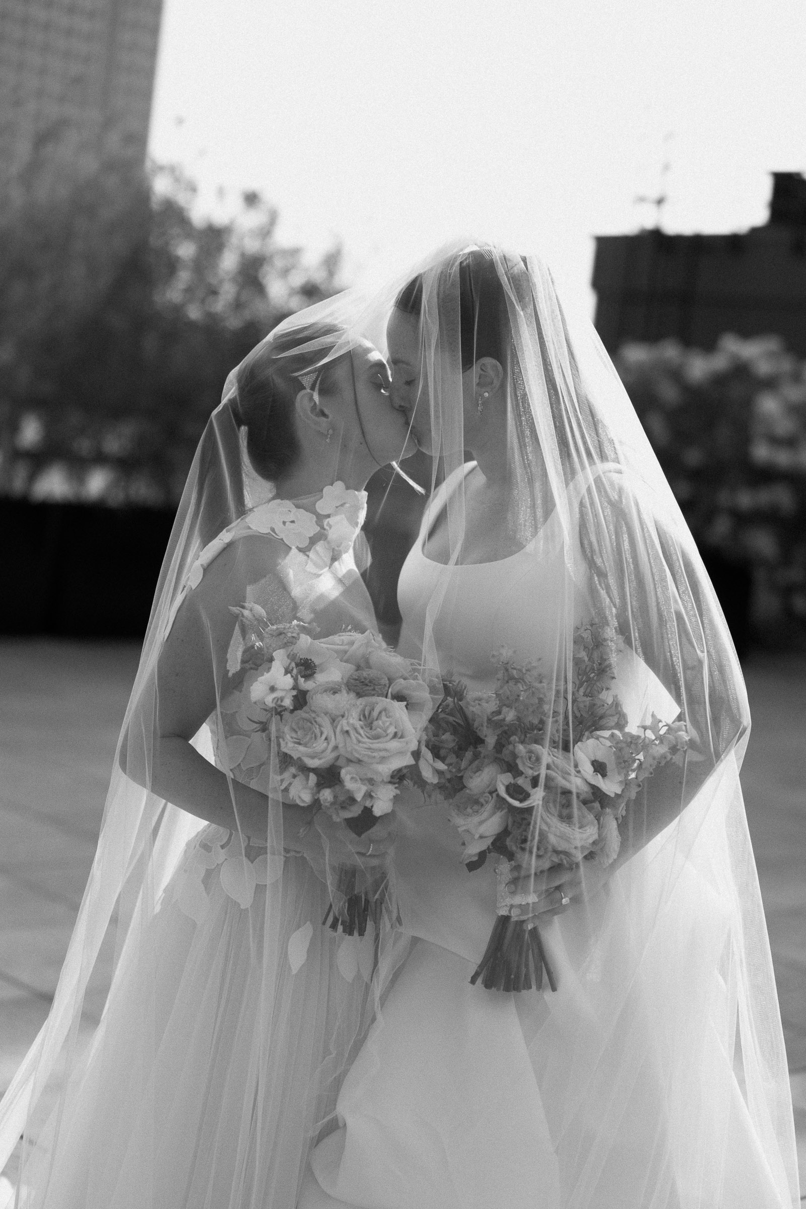Black-and-white portrait of one bride beneath her veil on the rooftop