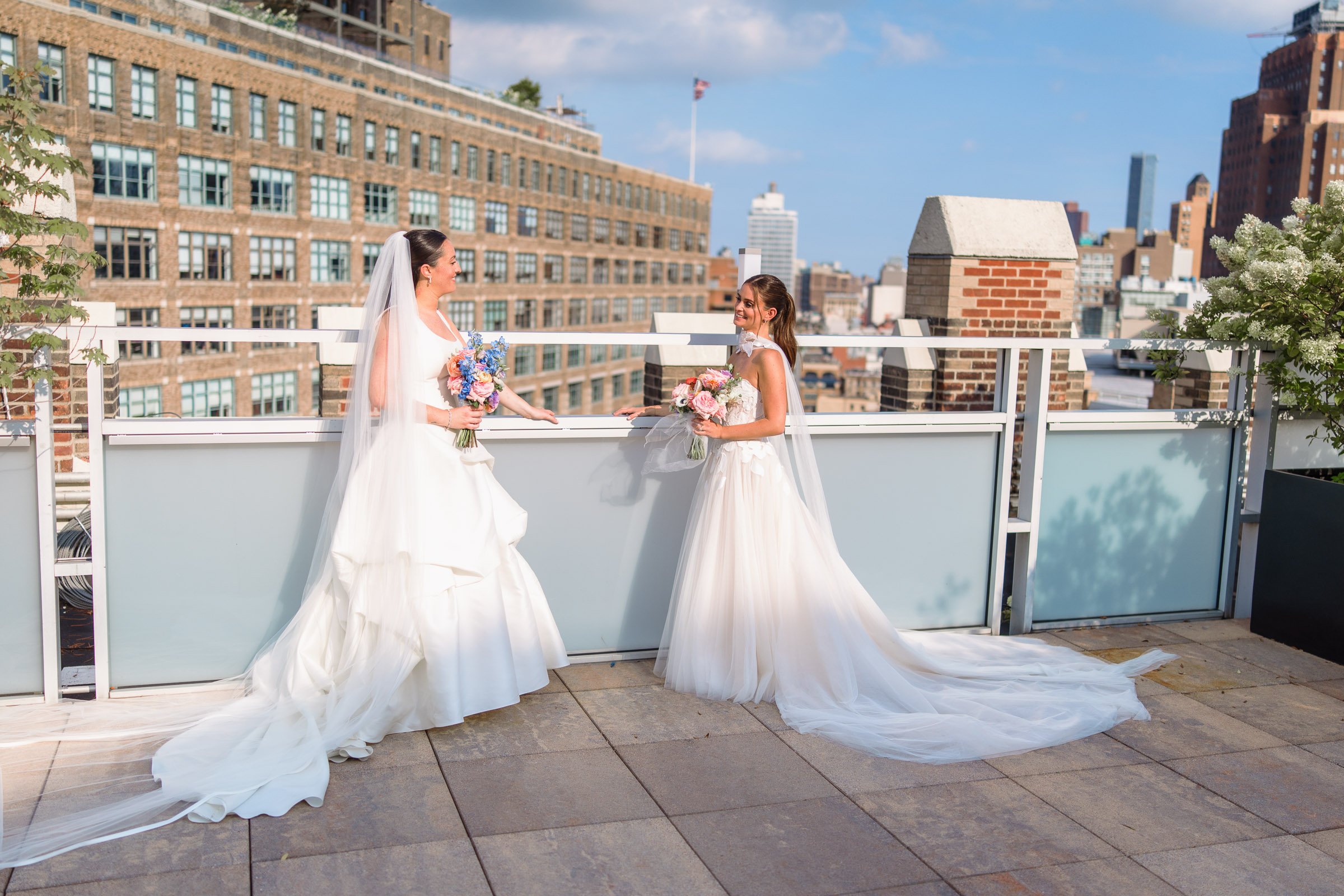 The brides standing together at the edge of the rooftop before the indoor ceremony
