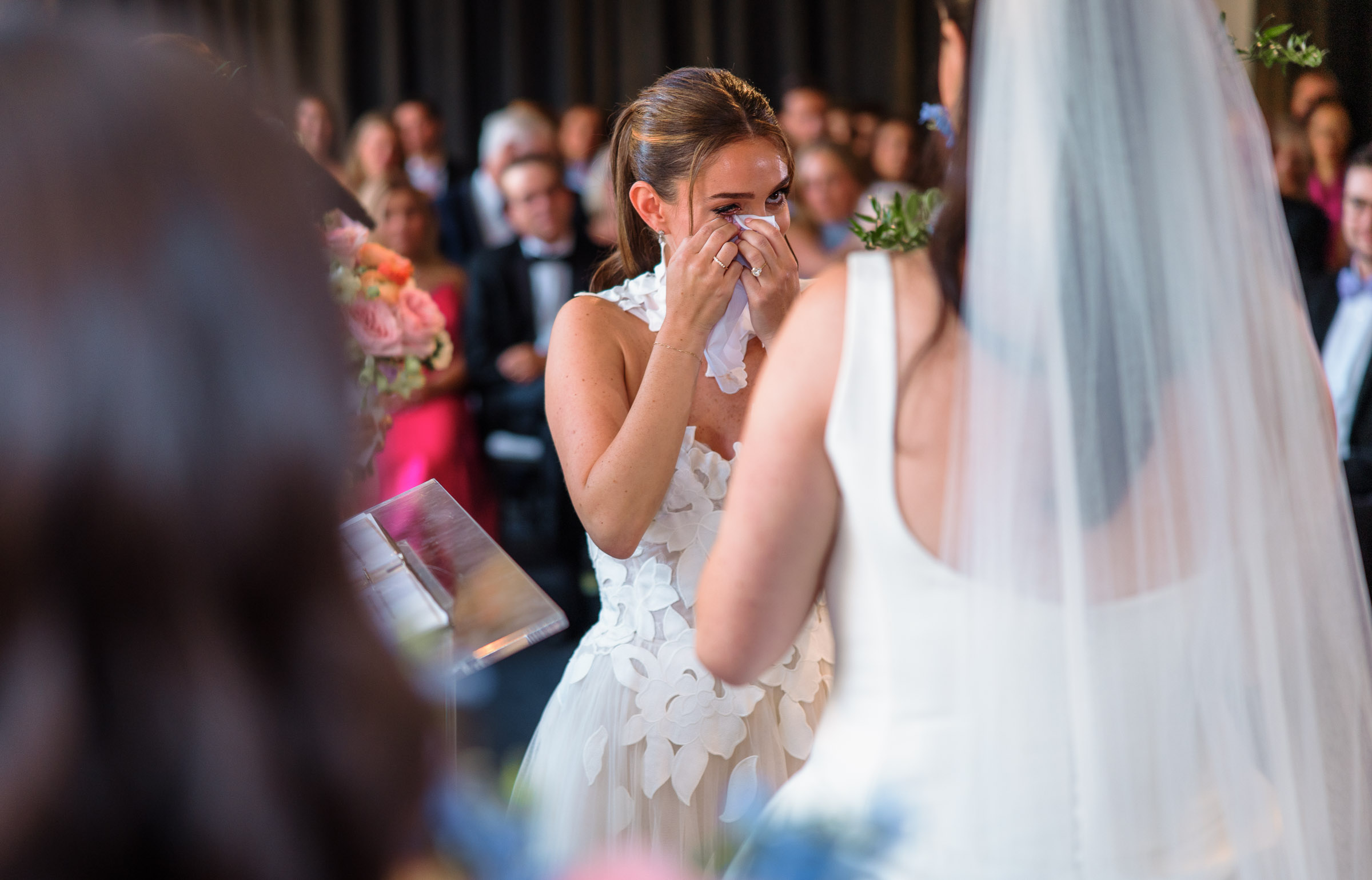 One bride smiling through tears while listening to her partner’s vows