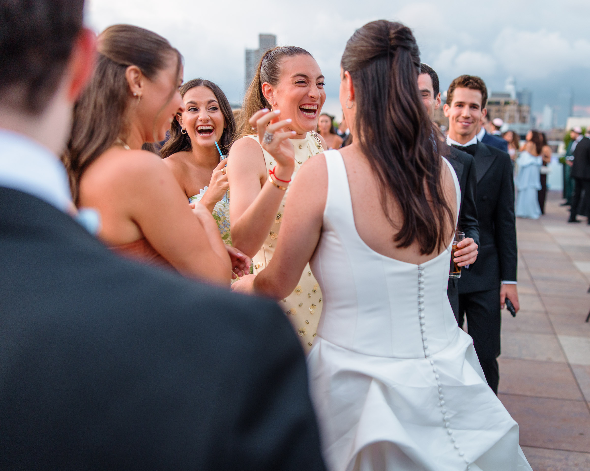 Sydney and Delilah laughing with friends and raising drinks during rooftop cocktail hour