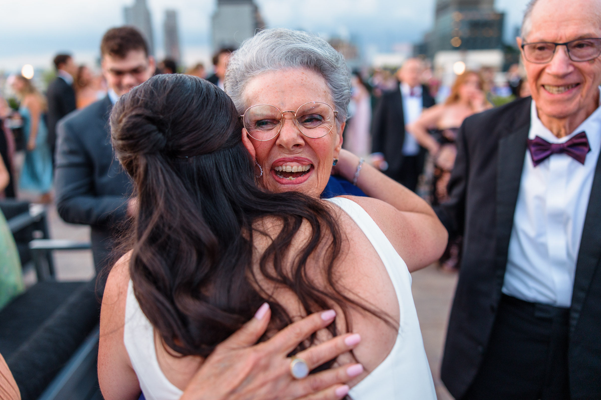 One of the brides embracing a family member during rooftop cocktail hour