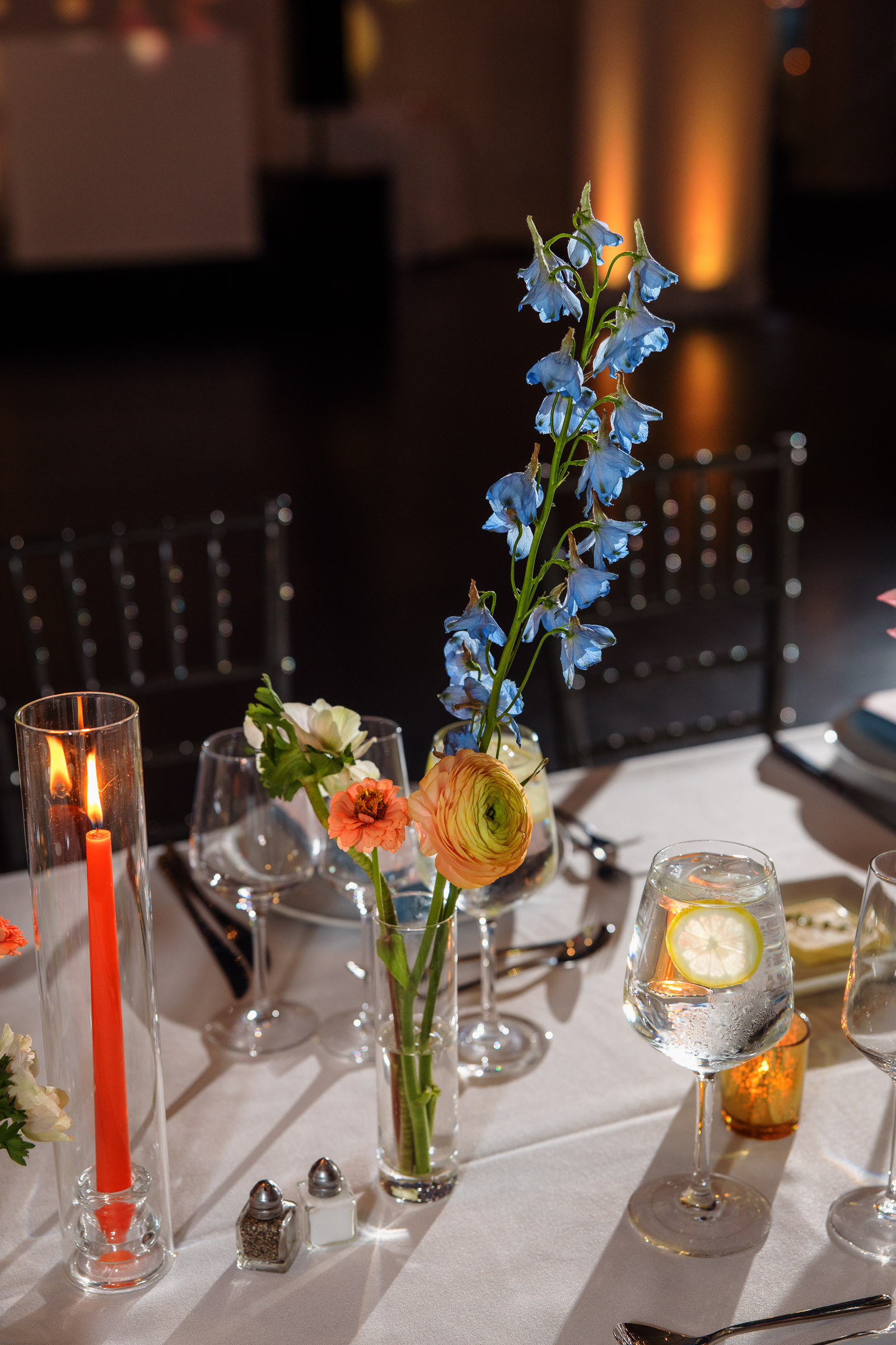 Pastel floral arrangements, candles, and place settings on a reception table