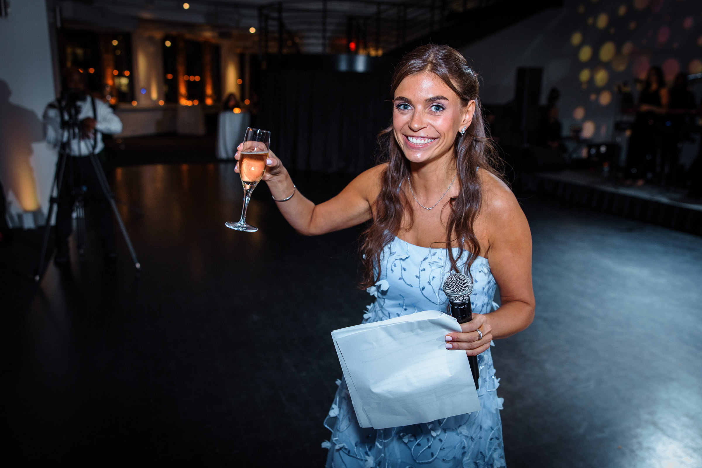 A wedding guest raising a champagne glass during a reception toast
